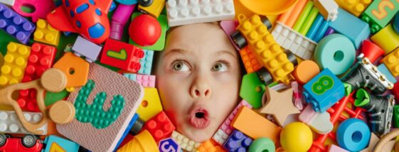 Funny,Surprised,Little,Girl,Lying,In,The,Chaos,Of,Toys.