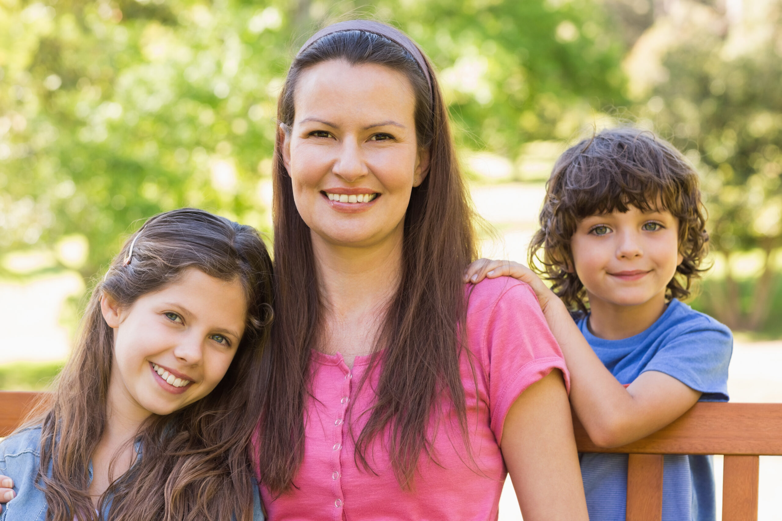 Portrait,Of,A,Smiling,Woman,With,Kids,Sitting,On,Park