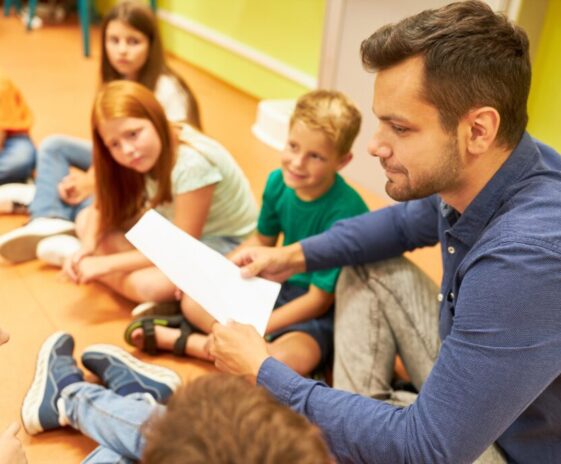 Side,View,Of,Male,Teacher,Holding,Sheet,Of,Paper,While