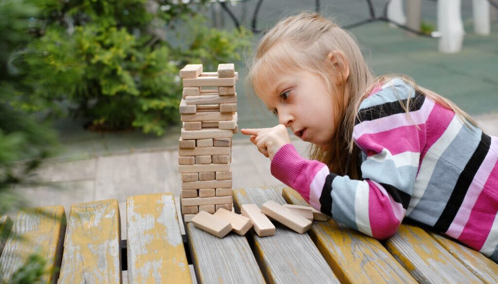 Person,Stacking,Wooden,Blocks,,Building,Tower,While,Seated,At,A
