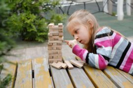 Person,Stacking,Wooden,Blocks,,Building,Tower,While,Seated,At,A