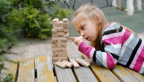 Person,Stacking,Wooden,Blocks,,Building,Tower,While,Seated,At,A