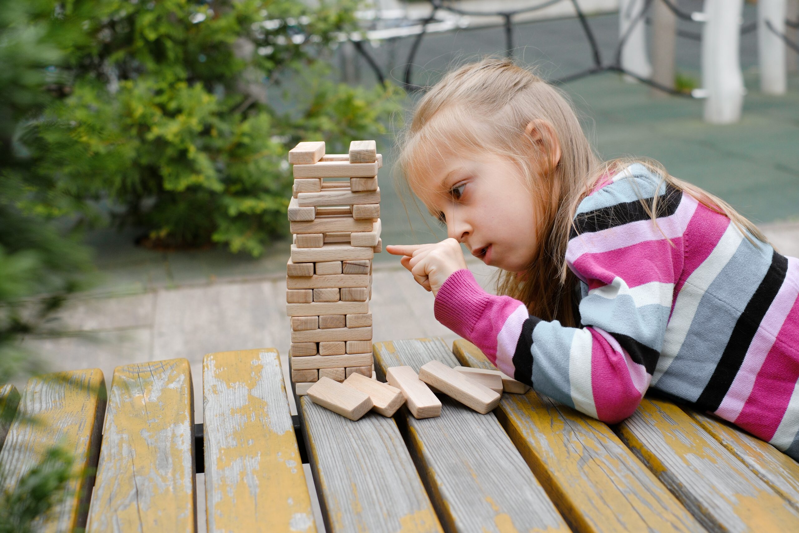 Person,Stacking,Wooden,Blocks,,Building,Tower,While,Seated,At,A